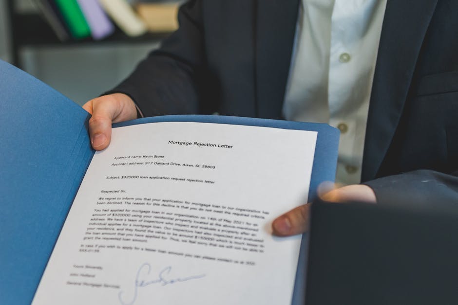 Close-up view of a person holding a mortgage rejection letter in a folder, indoors. - After you submit your documents
