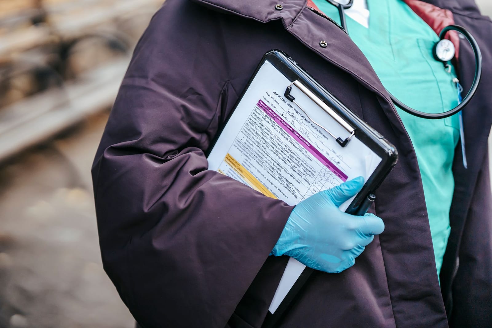 Crop anonymous female doctor in medical clothes and gloves with stethoscope standing outside with documents in clipboard - Medicaid & CHIP coverage