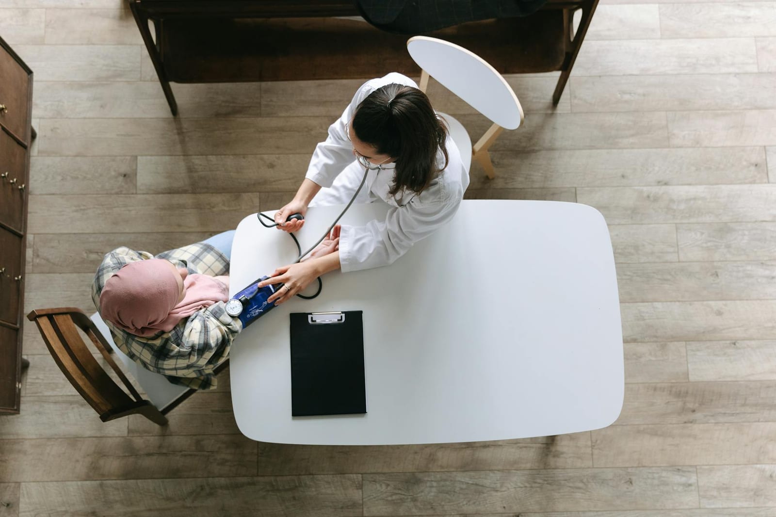 Overhead view of a doctor checking a patient's blood pressure during a healthcare consultation indoors. - If you had a Marketplace plan without the premium tax credit