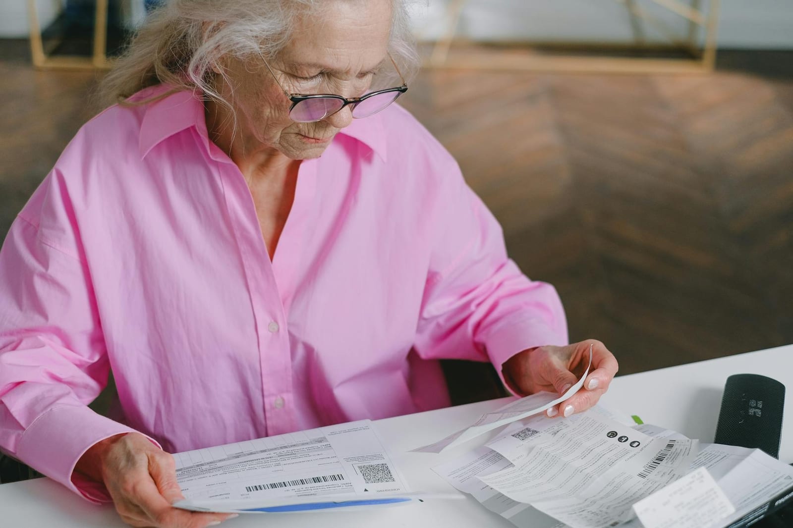 Elderly woman in pink blouse reading documents at a table indoors. - 2020 stand-alone dental plan (SADP) data