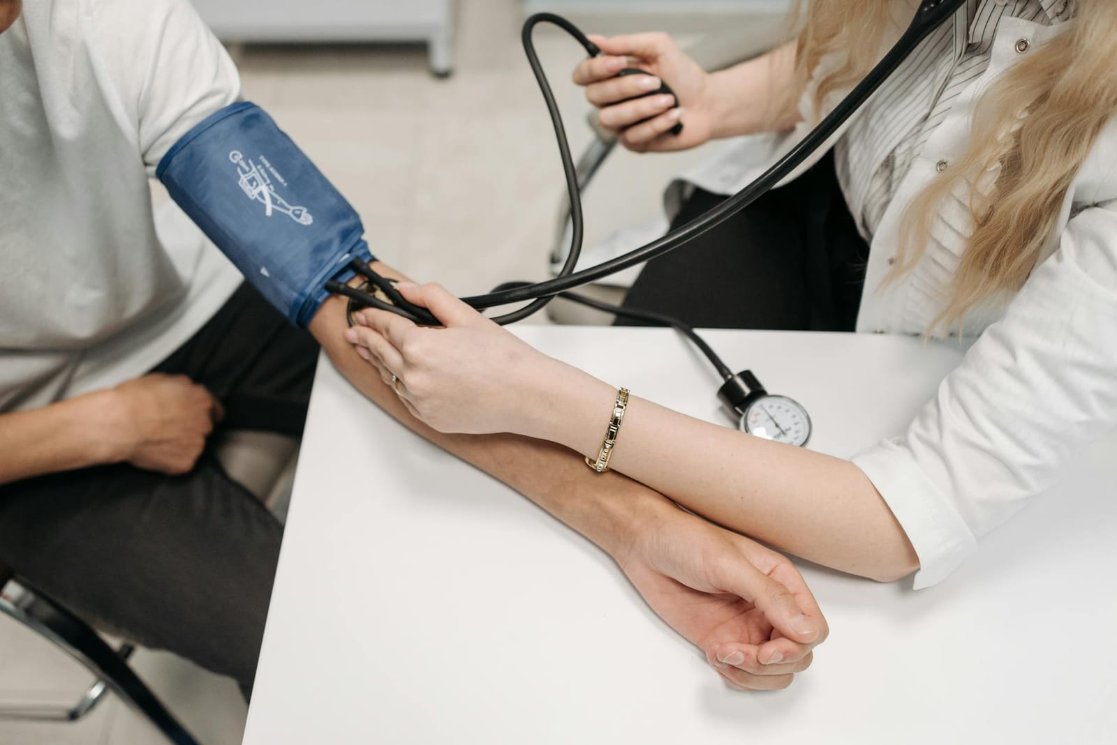 A doctor measures a patient's blood pressure with a sphygmomanometer during a consultation. - Other Health Coverage Questions