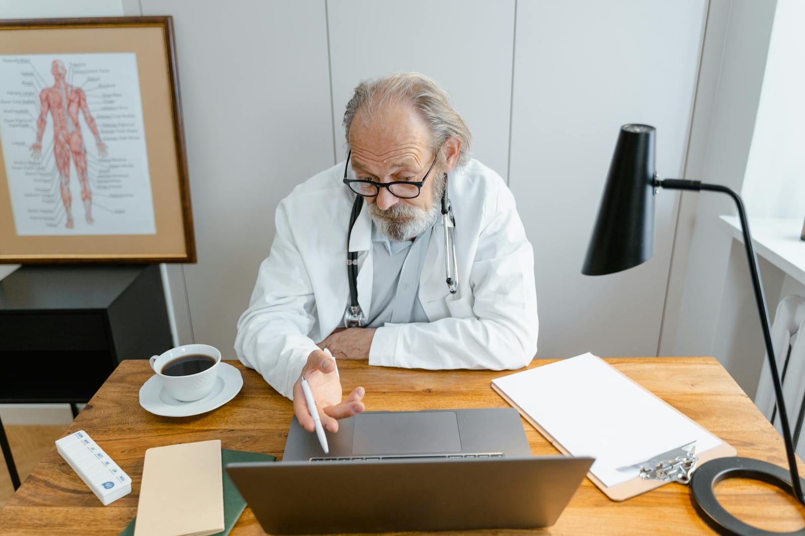Senior male doctor working on a laptop at his office desk with a cup of coffee. - Which changes to report to the Marketplace