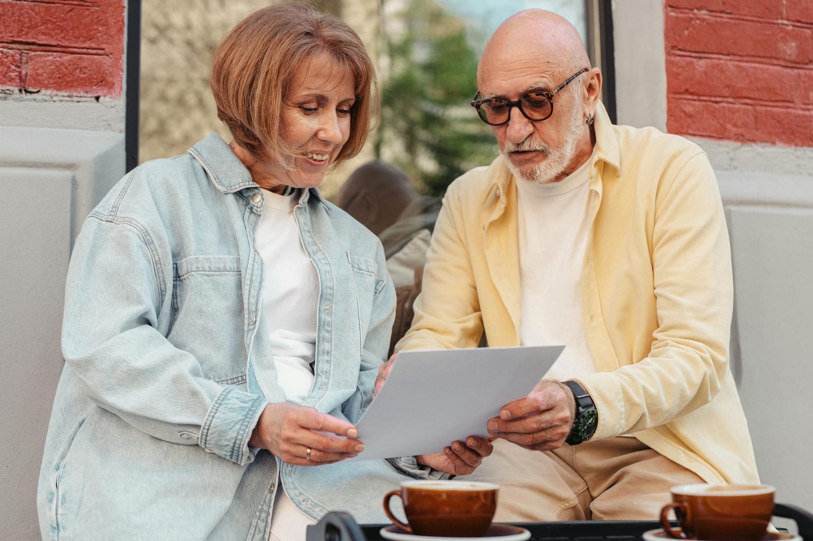 Elderly couple reading a document together while sitting outside at a cafe. - 2022 QHP landscape data