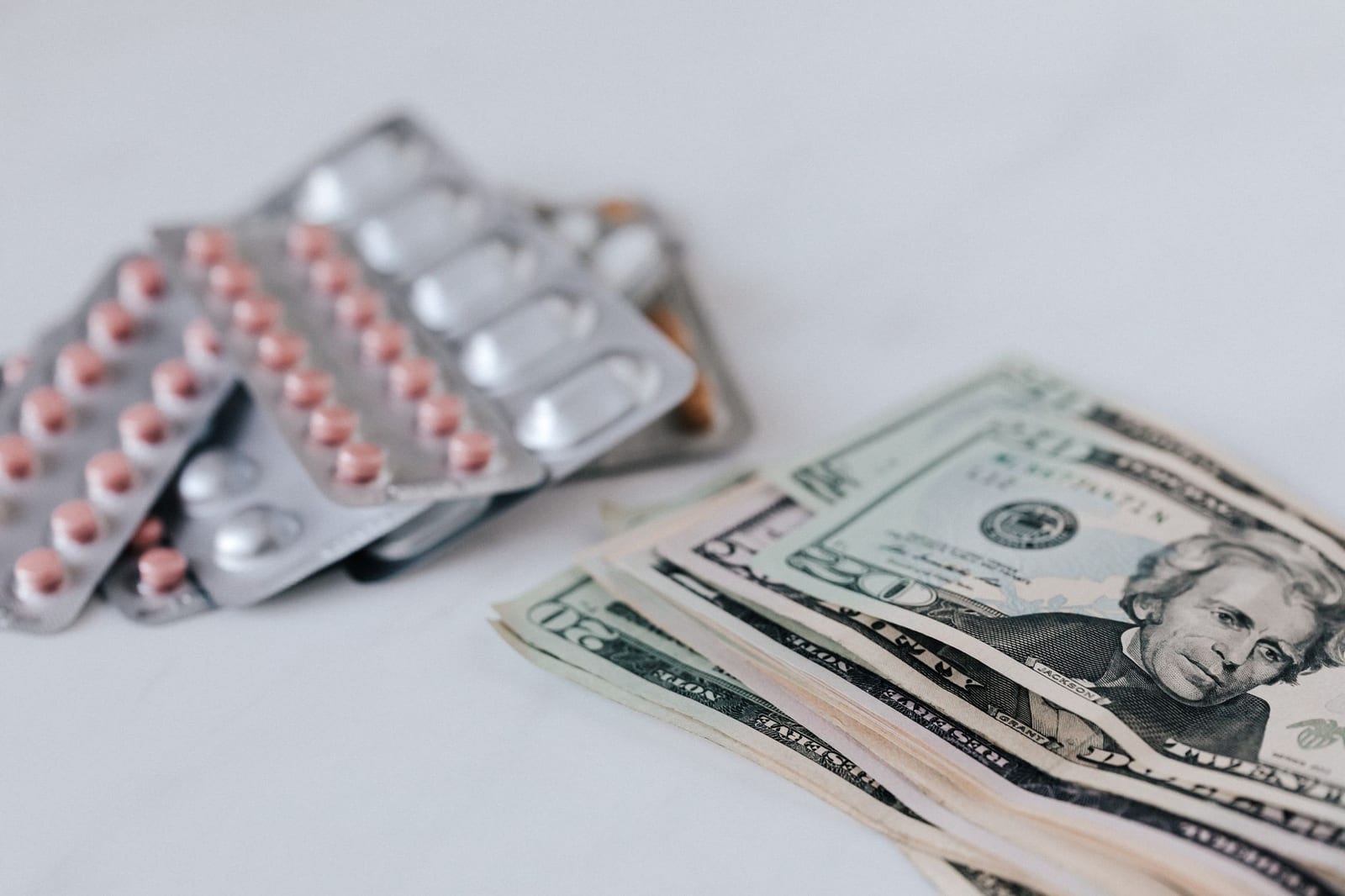 Heap of similar American dollars in cash placed near blisters of expensive drugs on white table - Submit documents to confirm denial of Medicaid or CHIP coverage