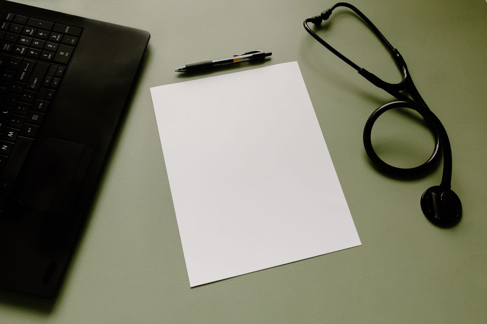 Professional workspace featuring a laptop, stethoscope, pen, and paper sheet for healthcare tasks. - 2023 SHOP health plan information for small businesses