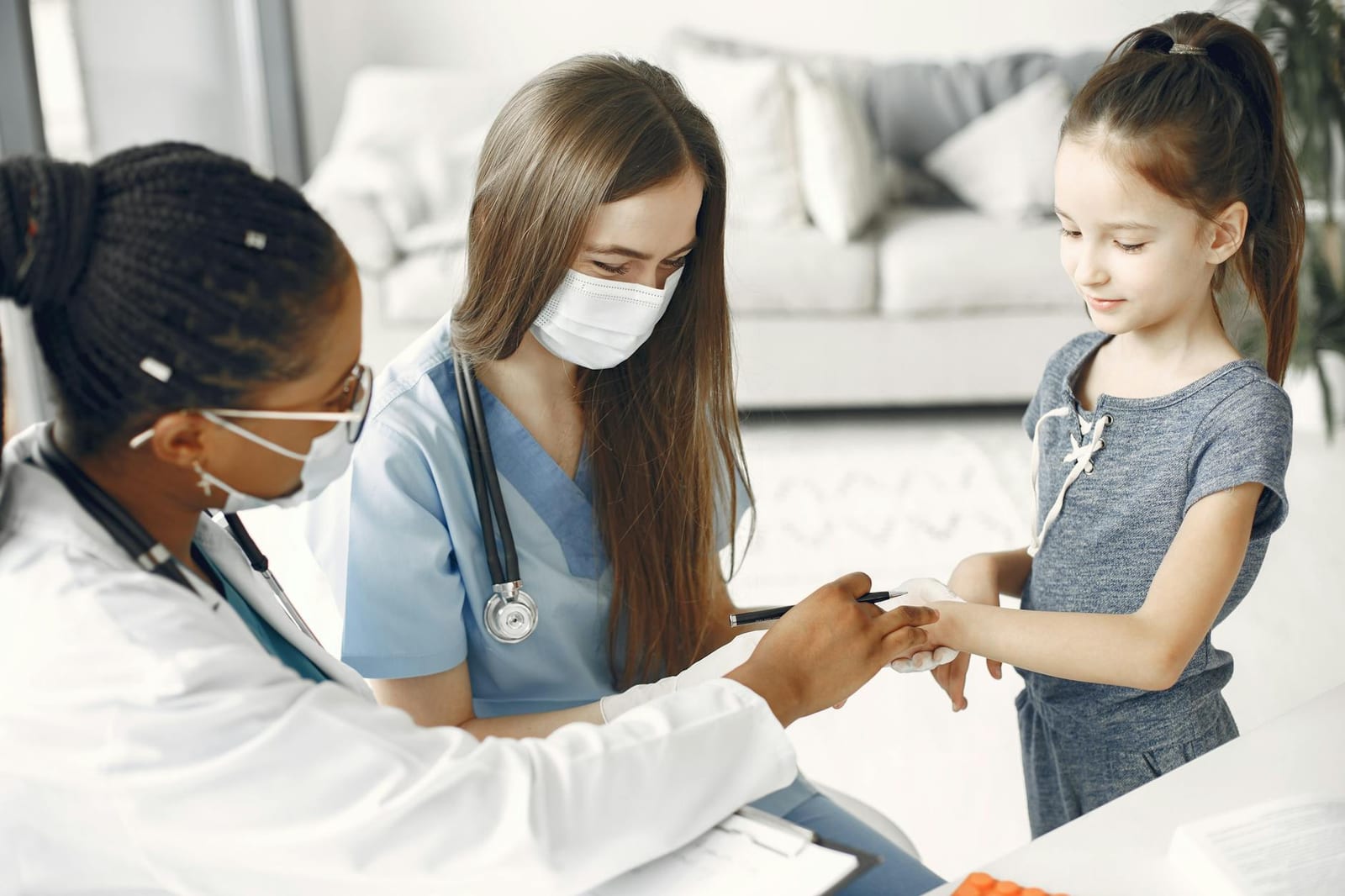 Doctors and a nurse wearing masks attending to a child for a healthcare checkup. - If you have job-based insurance