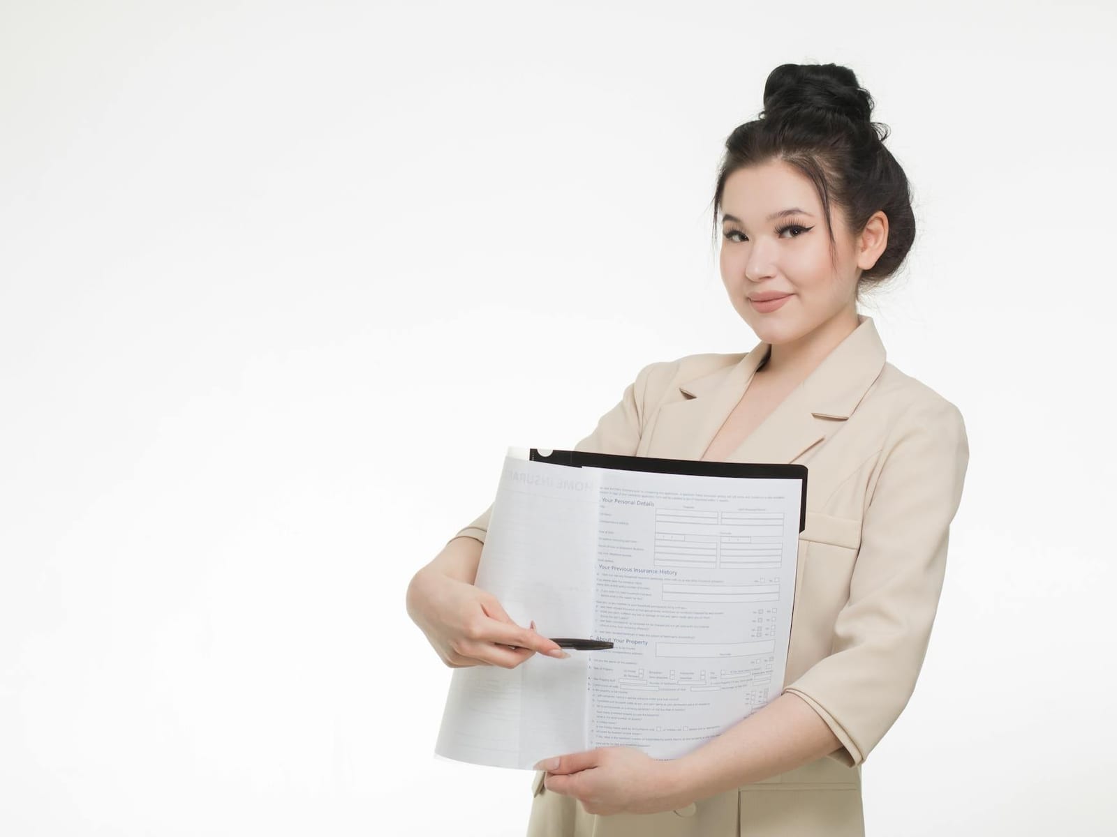 Smiling businesswoman in beige blazer holding and pointing to documents against white background. - Why bother with health insurance?