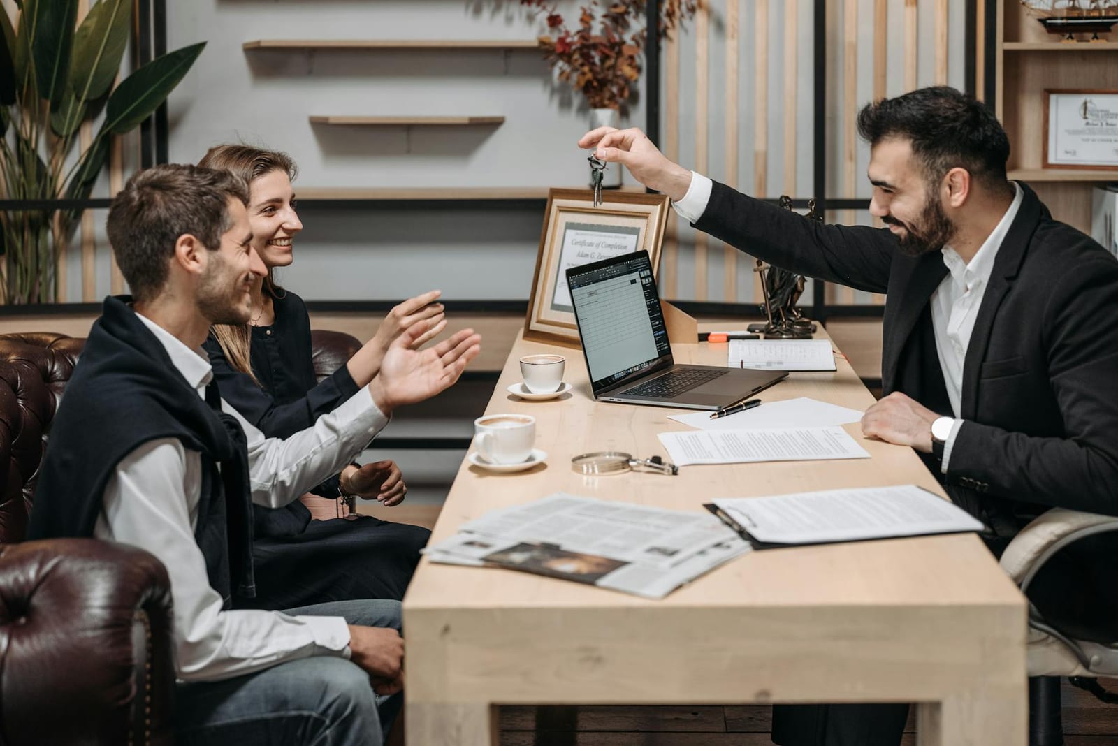 Business professional handing keys to smiling clients at an office desk during a consultation. - No health coverage for 2018