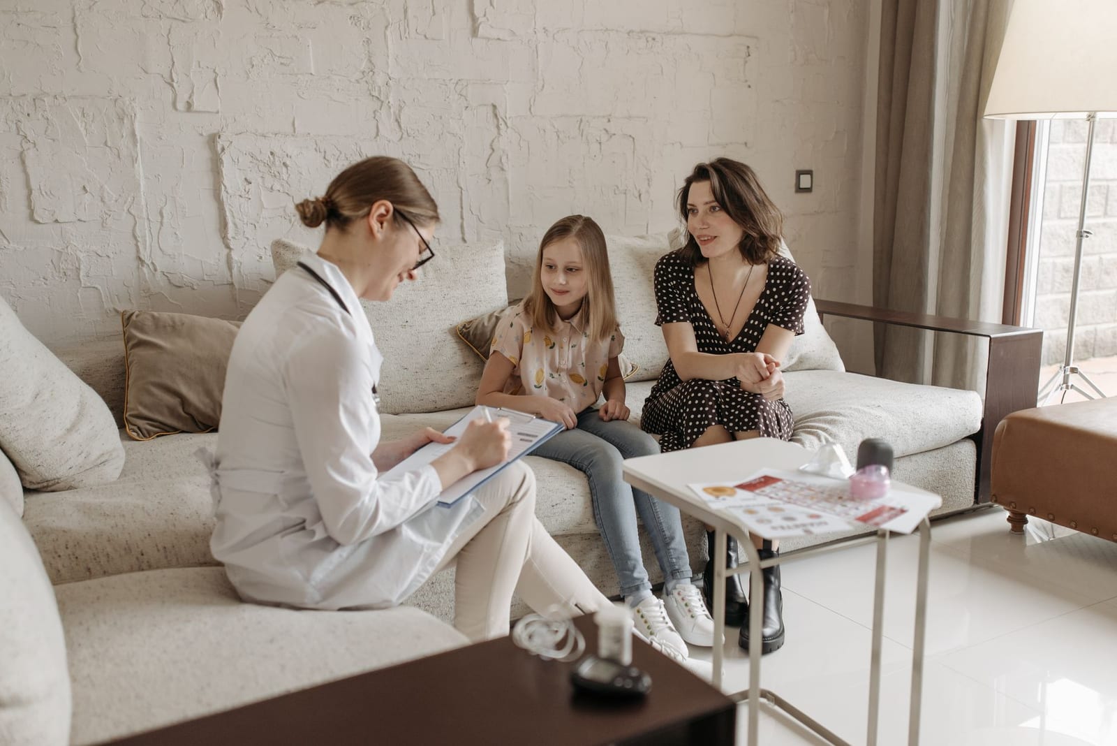 A doctor consults with a mother and daughter in a cozy indoor setting. - Health services through Indian programs