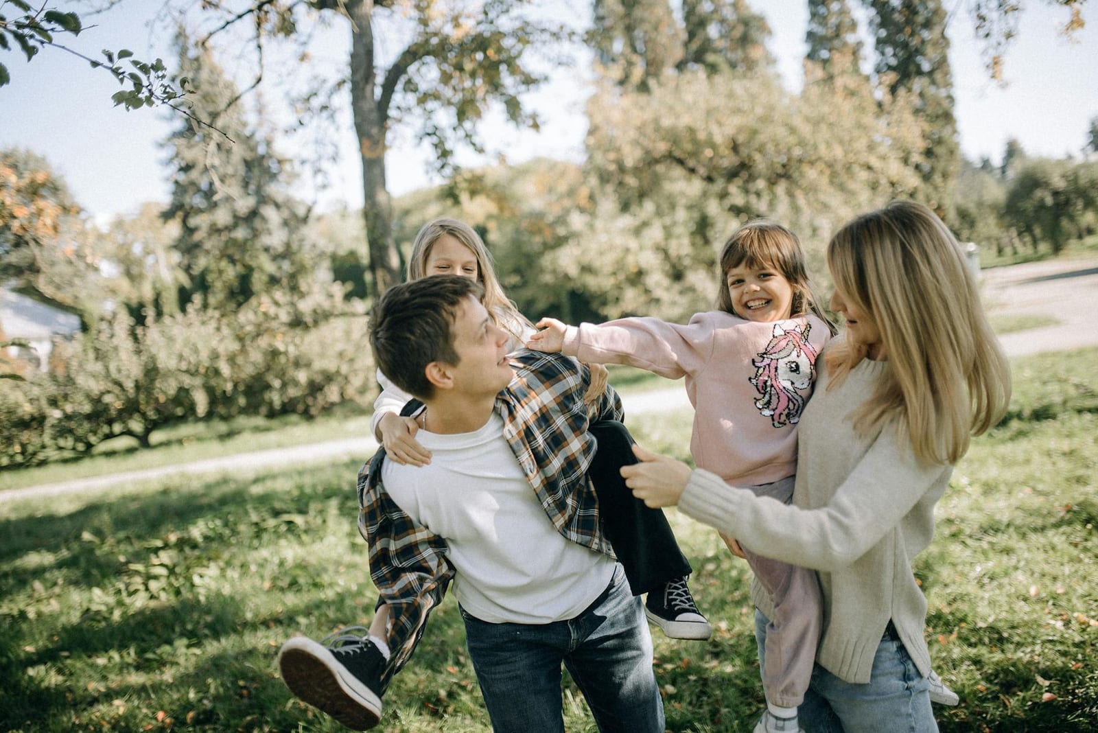 A joyful family spending quality time together in a green park on a sunny day. - Terms & Conditions