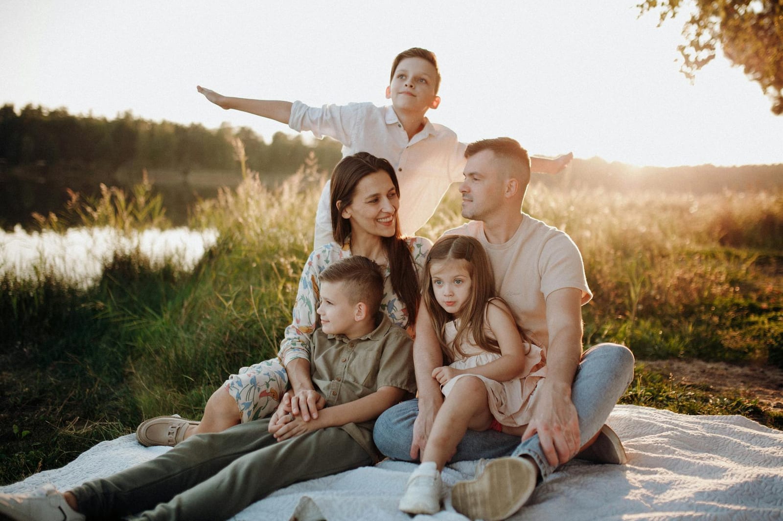 A family of five enjoying a serene picnic in a sunlit meadow during sunset. - Submit documents to confirm marriage