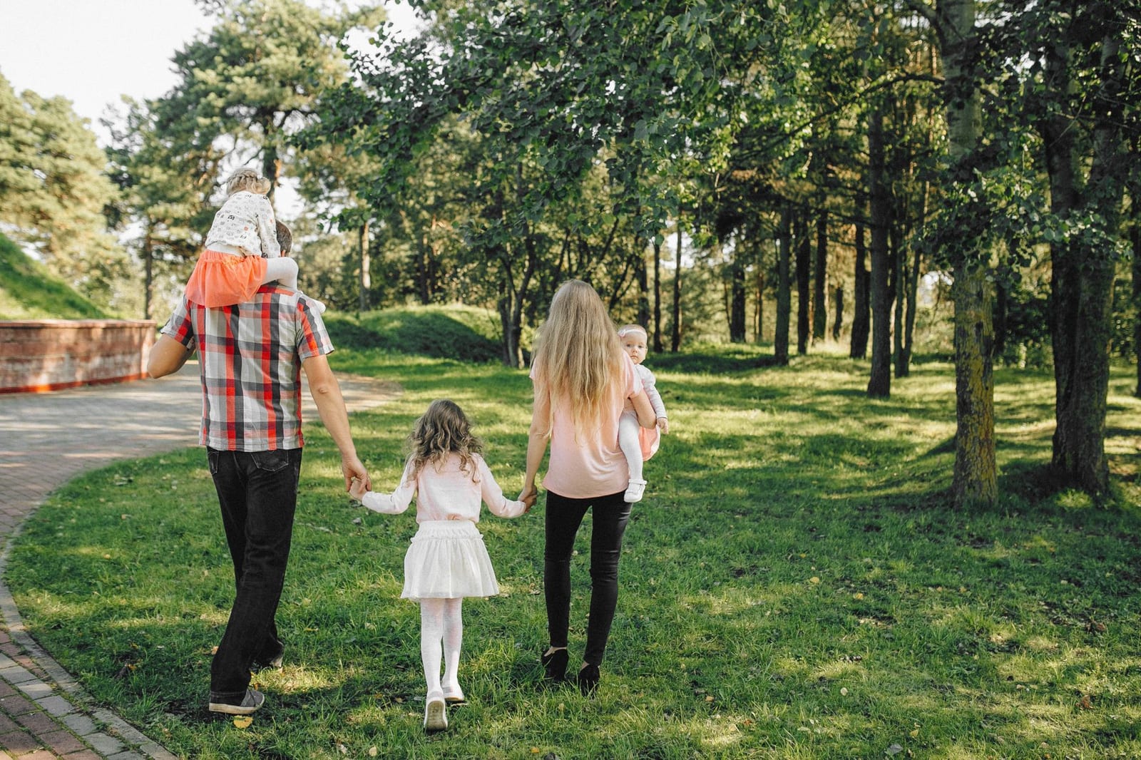 A family enjoying a walk under dappled sunlight in a lush green park. - 2015 QHP landscape data