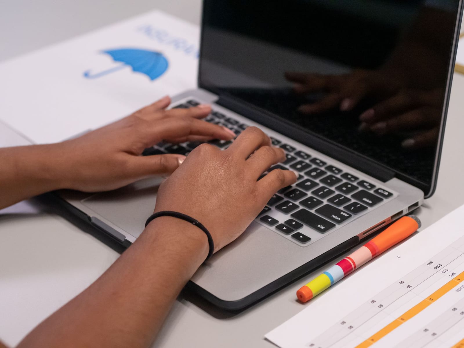 A person works on a laptop with colorful markers and a printed chart nearby. - Health coverage if you're self-employed
