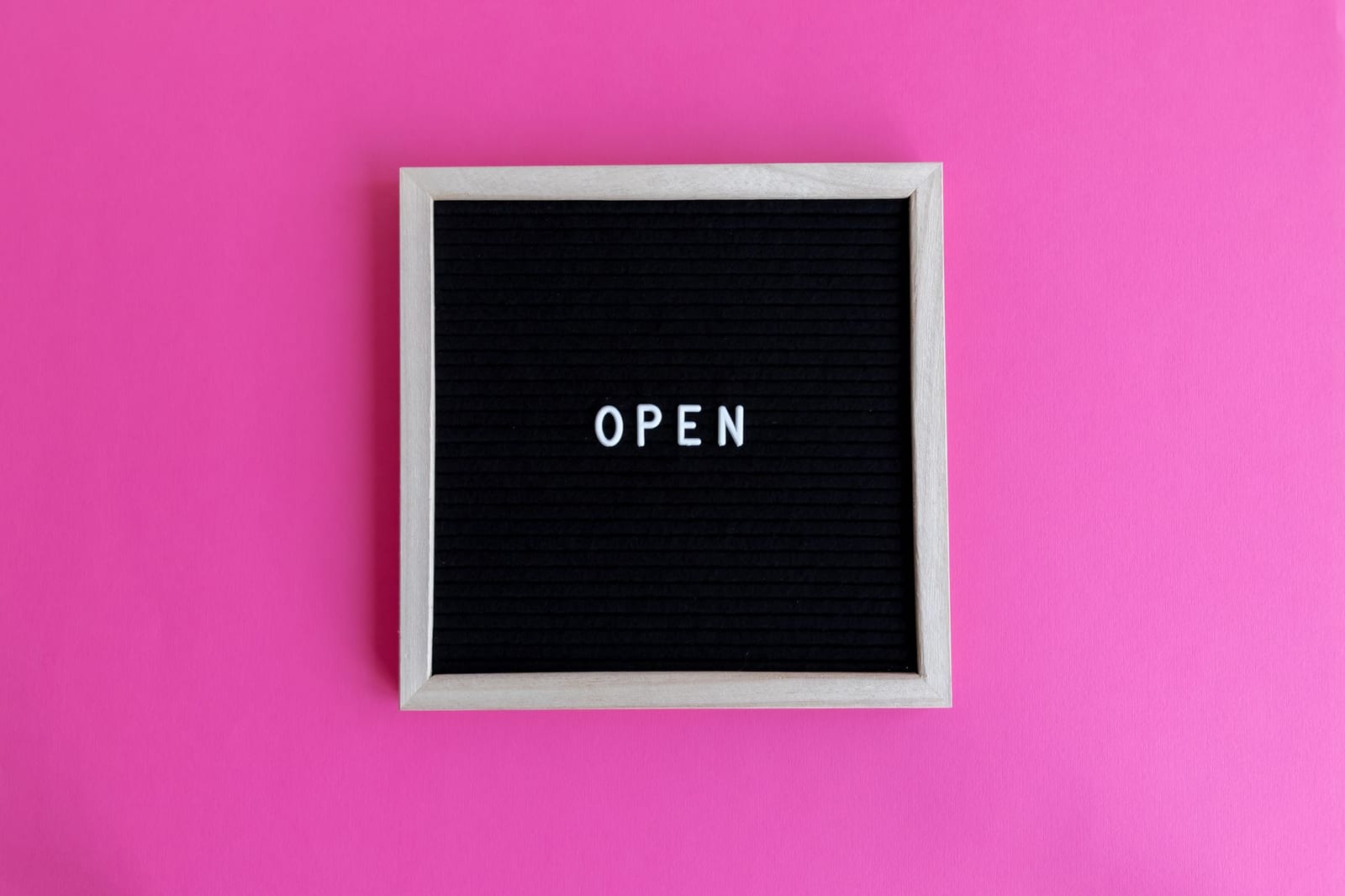 Framed letter board displaying 'Open' on a vibrant pink background, perfect for business or creative concepts. - Health coverage for immigrants
