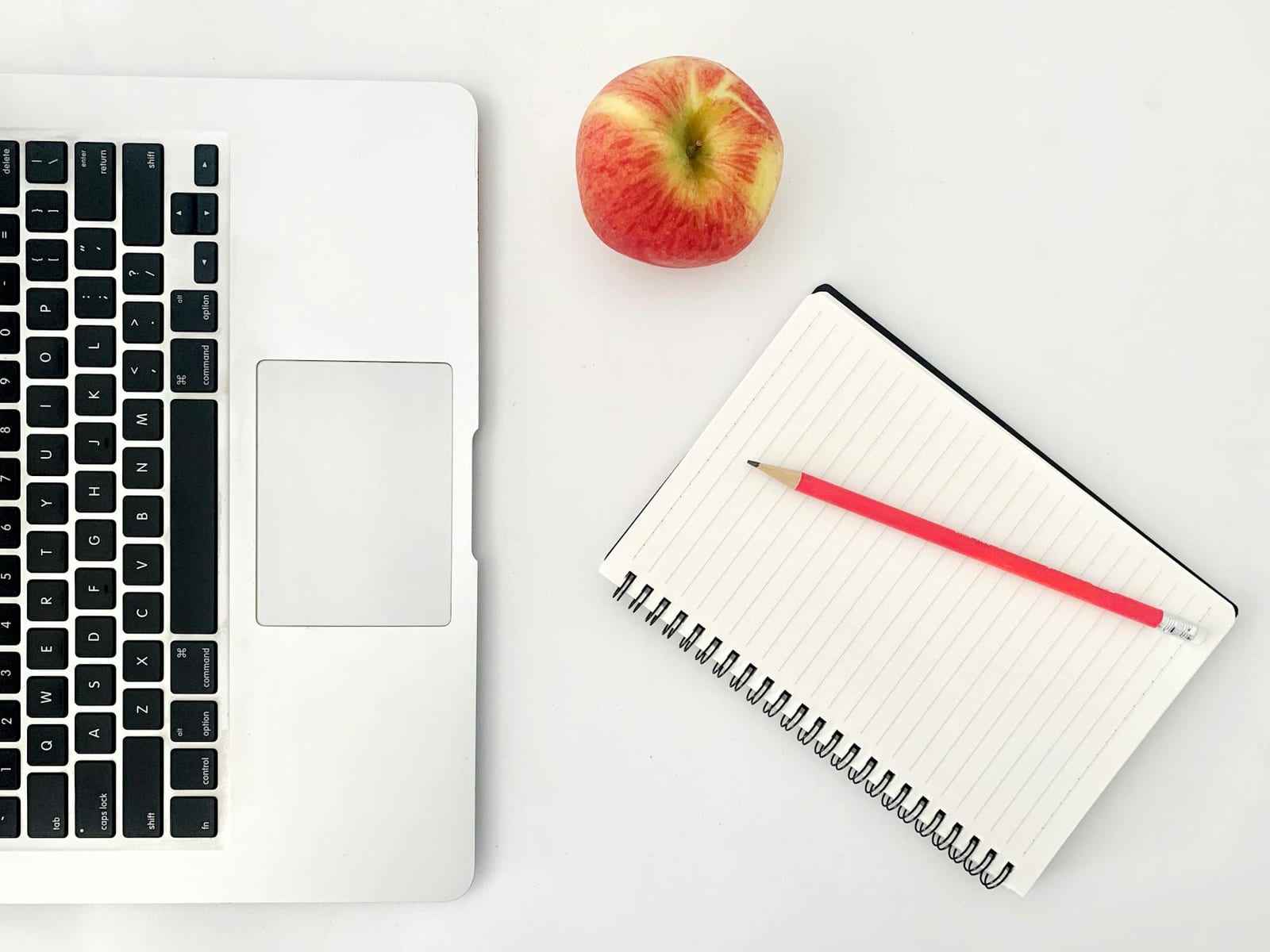 Top view arrangement of modern netbook keyboard placed on white table near opened notebook with blank sheets and red apple - 2018 stand-alone dental plan (SADP) data