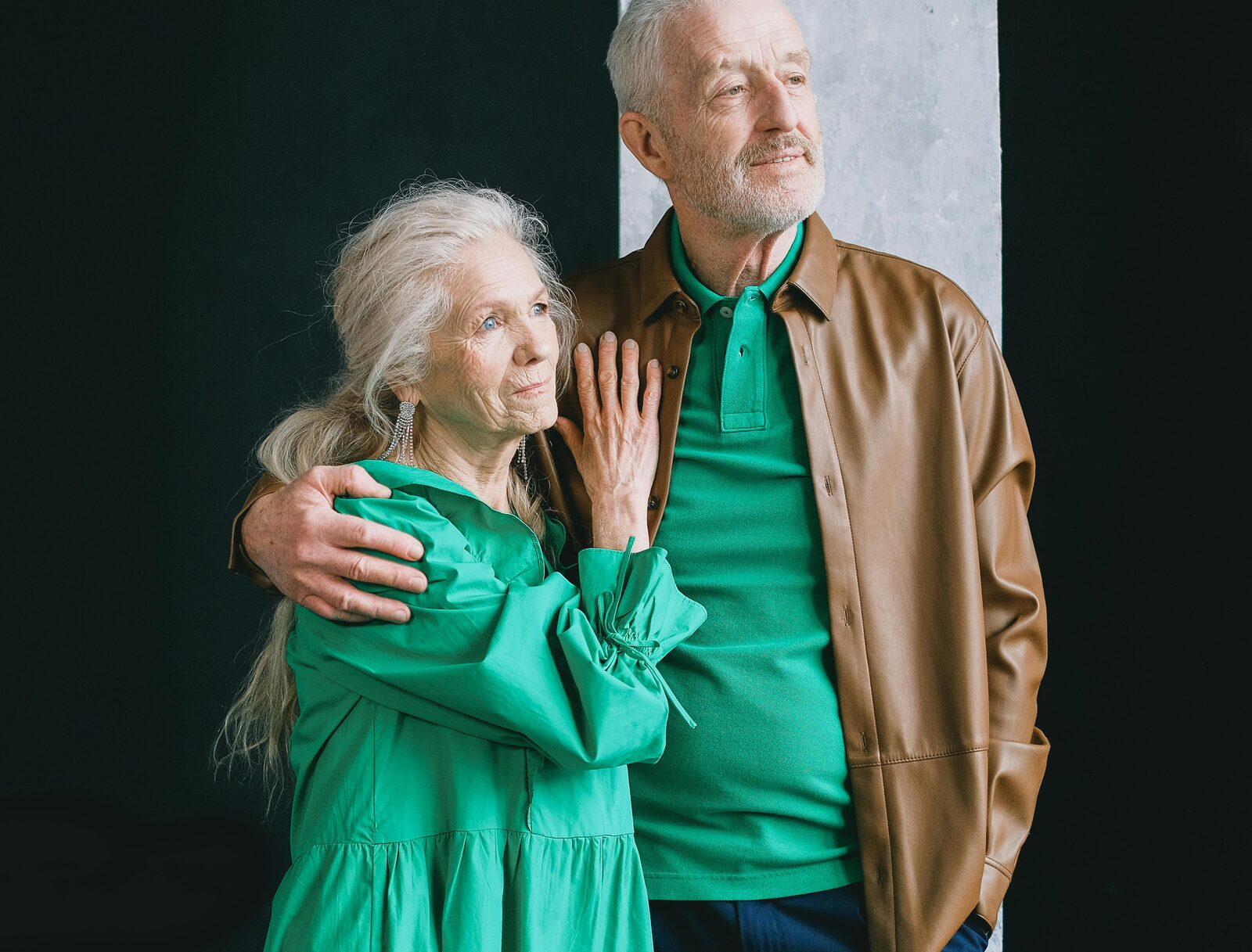 Medicare Advantage & Supplements — Elderly couple in green and brown outfits standing close together against a dark background, representing Medicare coverage for seniors.