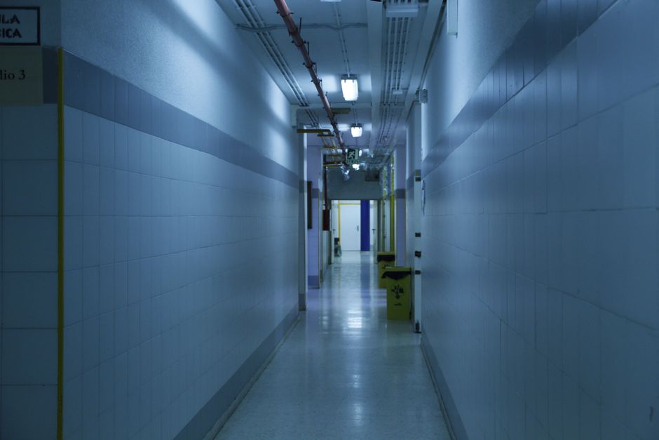 A deserted, dimly lit hallway with tiled walls and overhead lights. health insurance