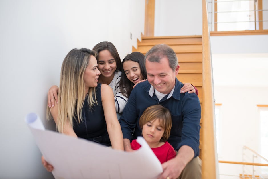 A joyful family gathers on a staircase, reviewing building plans indoors. health insurance