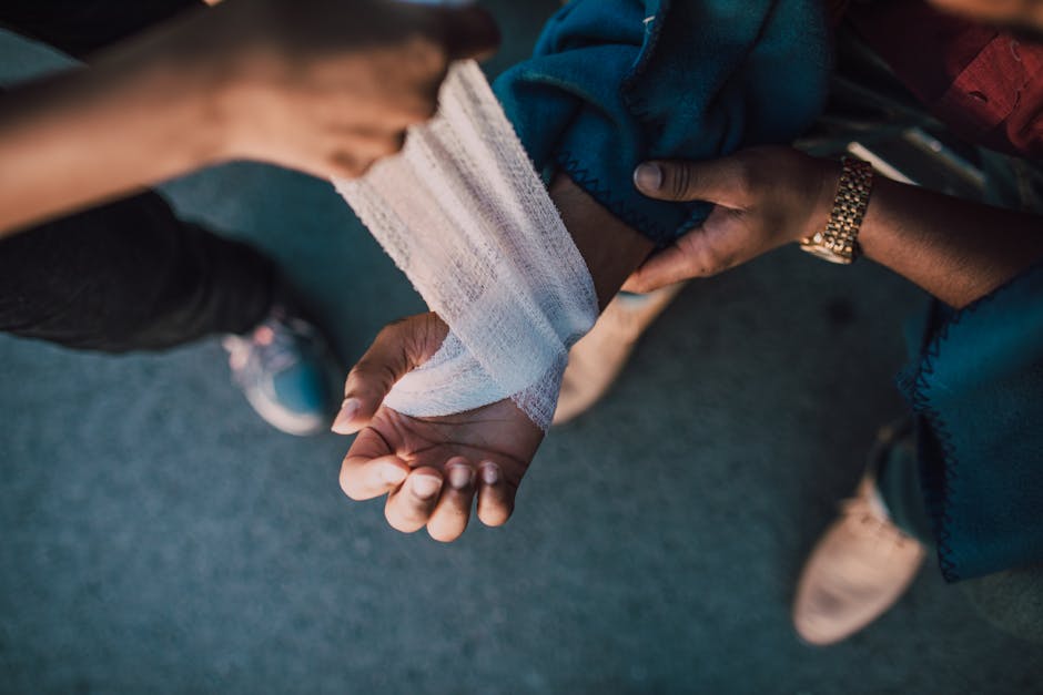A detail shot showing hands applying a bandage to an injured wrist outdoors. health insurance
