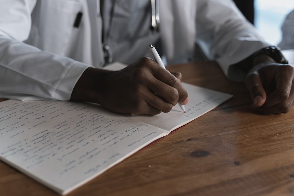 Close-up of a doctor writing notes with a pen in a medical notebook on a wooden desk. health insurance