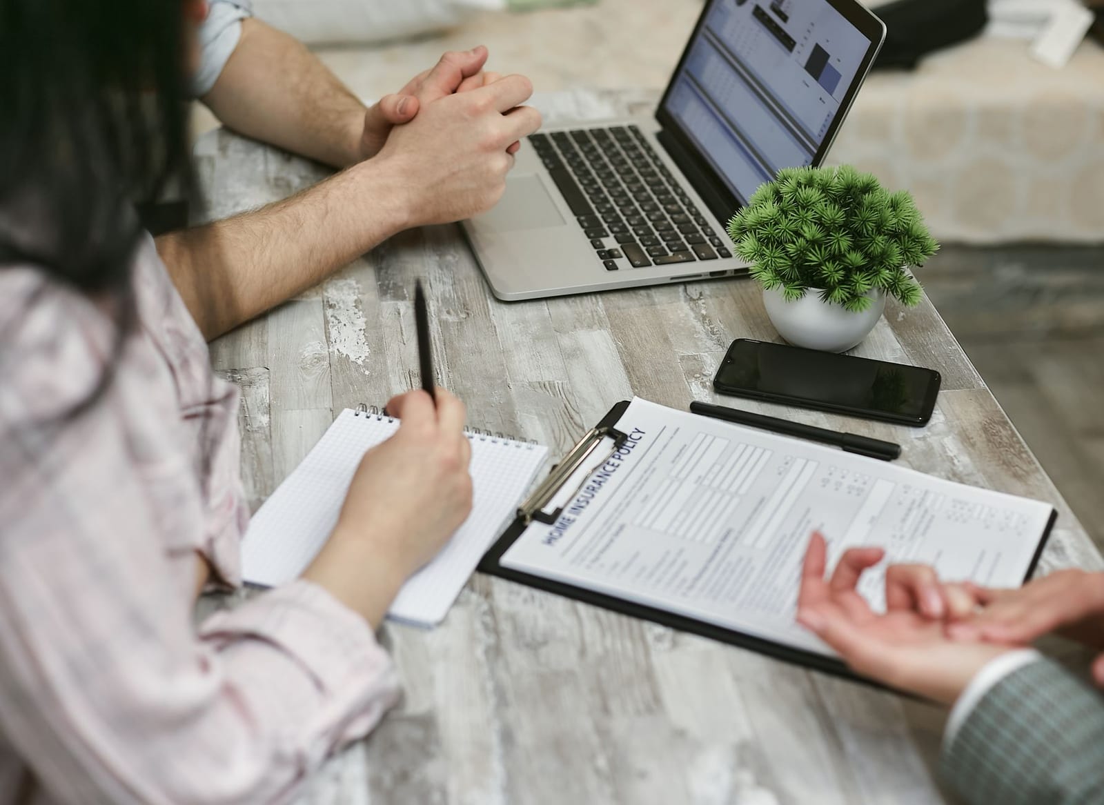 Professionals discussing home insurance policy over laptop and notes in an office setting. health insurance