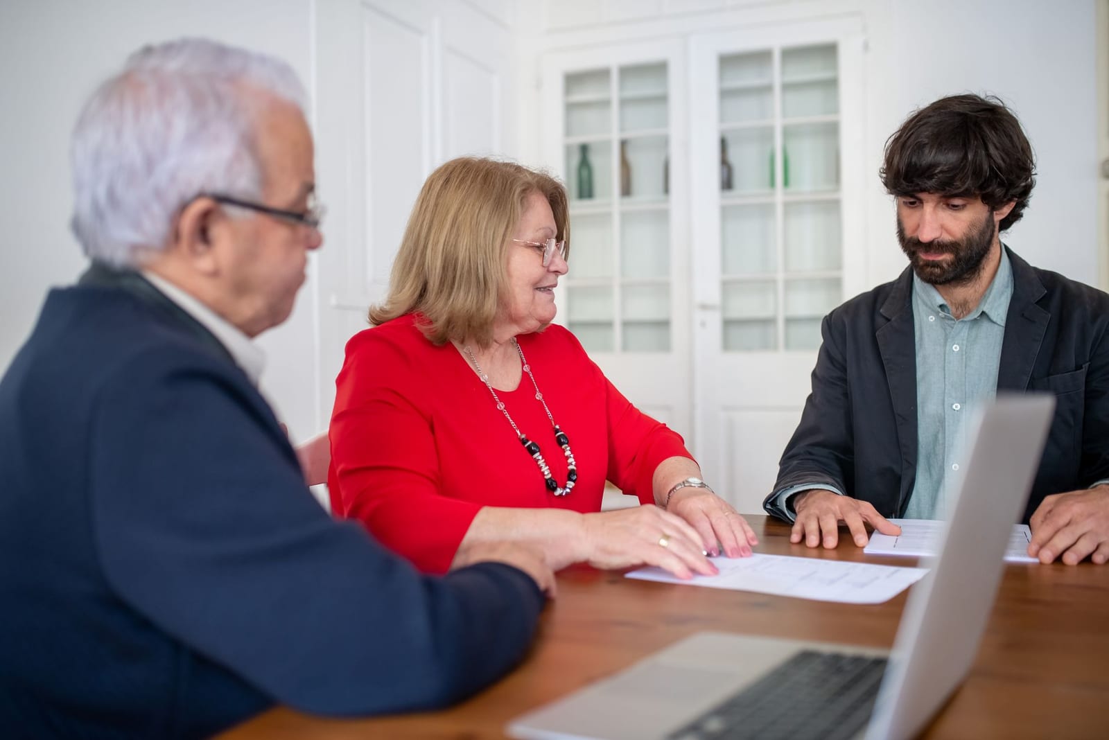 Three business professionals in a meeting, discussing documents and planning strategies indoors. health insurance