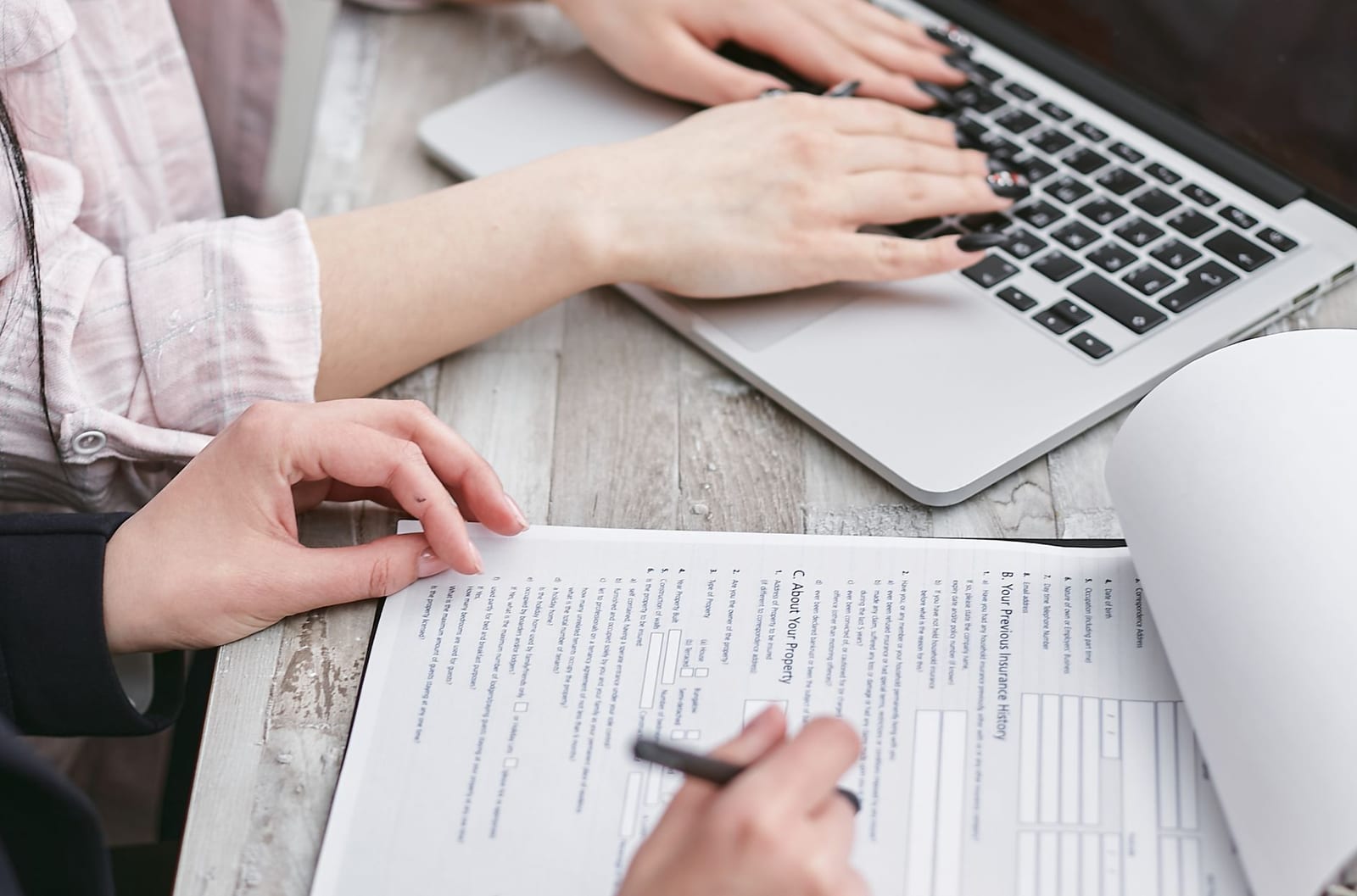 Close-up of hands typing on a laptop and reviewing business documents, focused on finance and legal tasks. health insurance