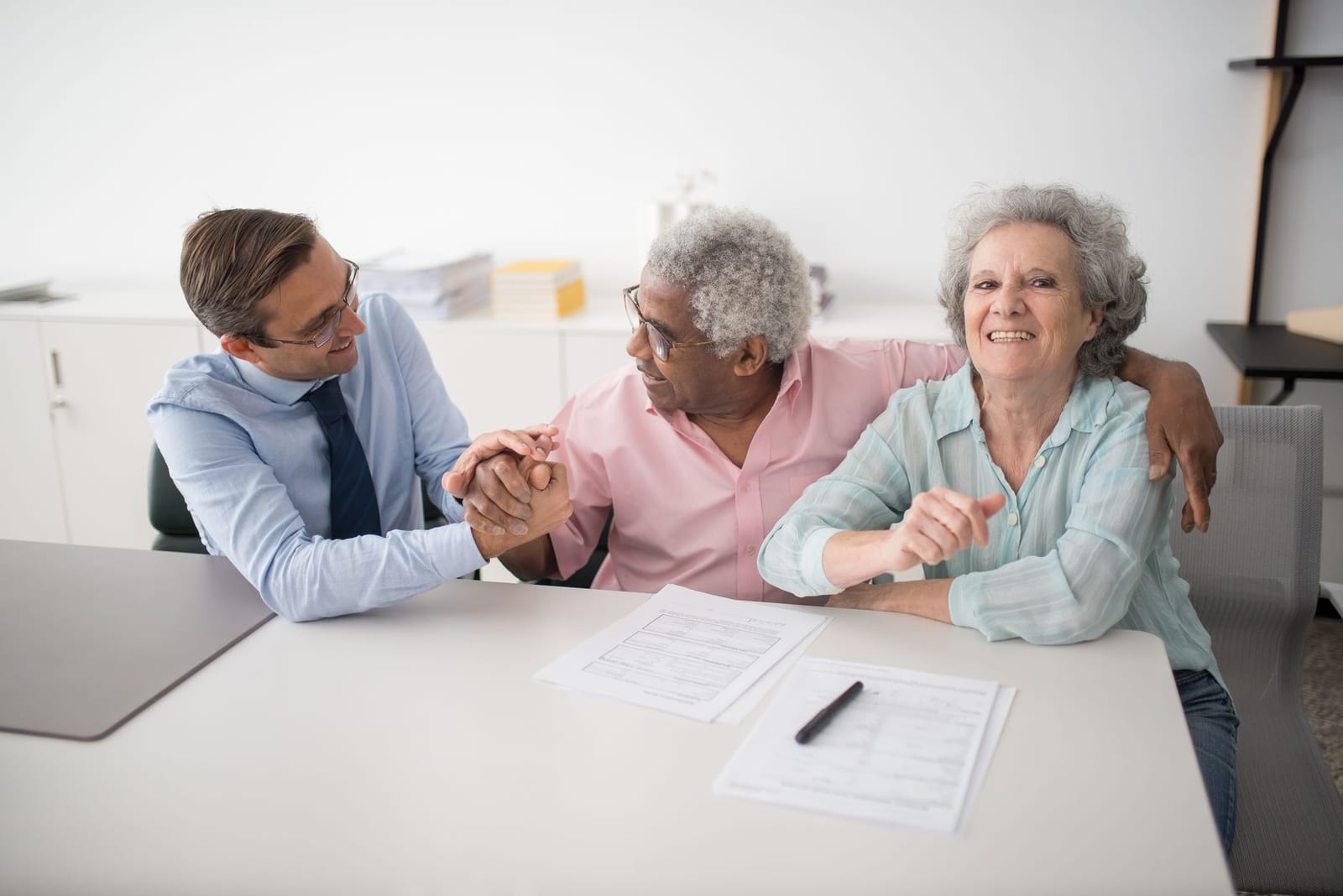 Senior couple in office meeting with consultant, discussing financial documents and smiling. health insurance