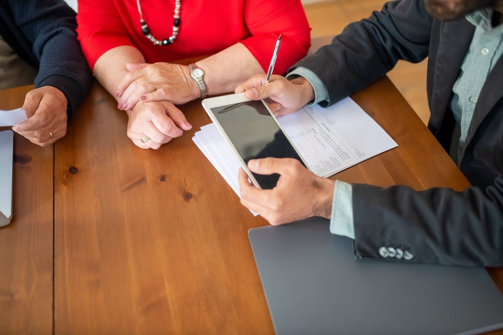 Business meeting at a wooden table with consultant reviewing documents and using a digital tablet. health insurance