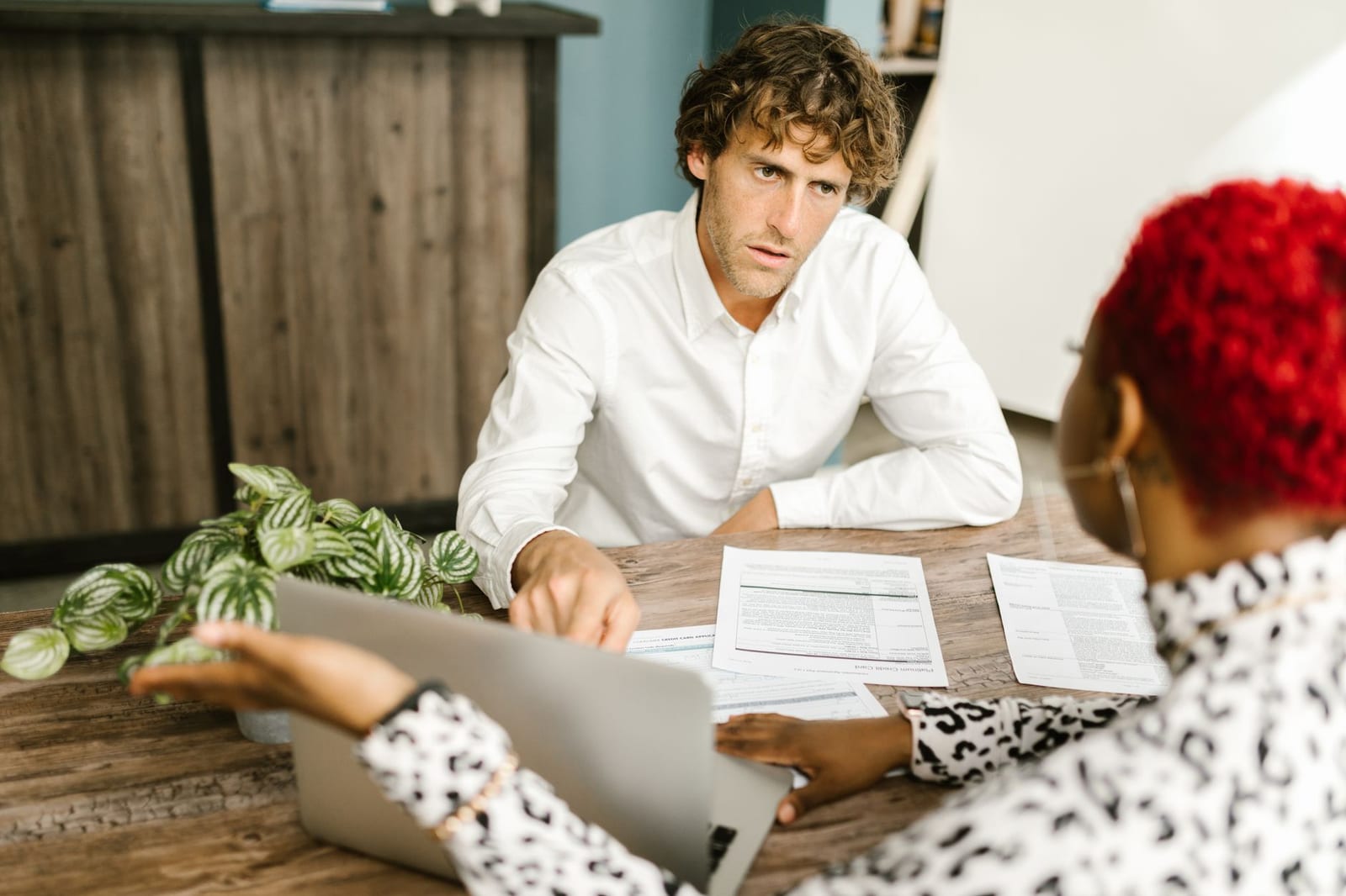 Business professionals discussing documents at a wooden table in an office setting. health insurance