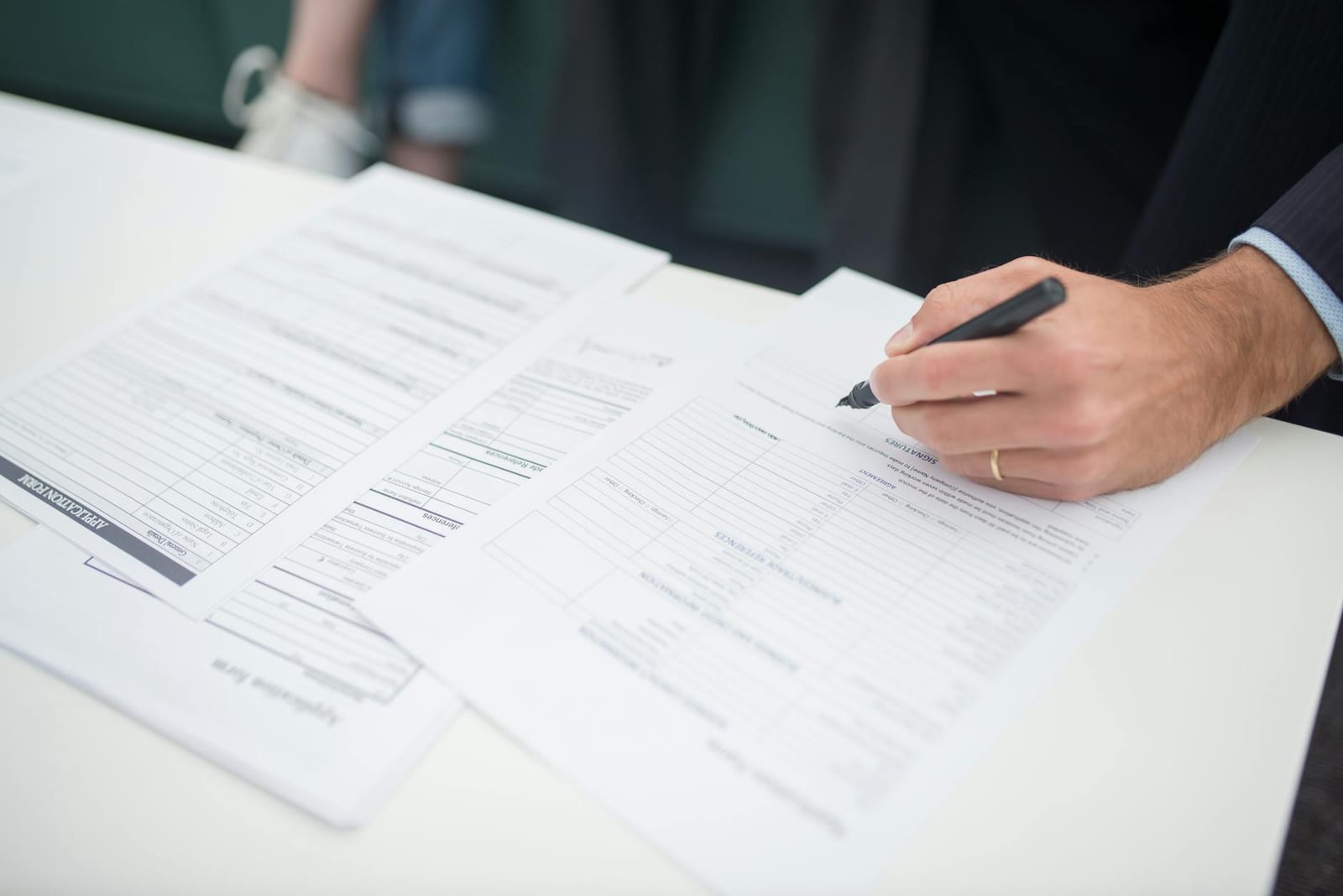 Close-up of a hand signing insurance documents in an office setting. health insurance