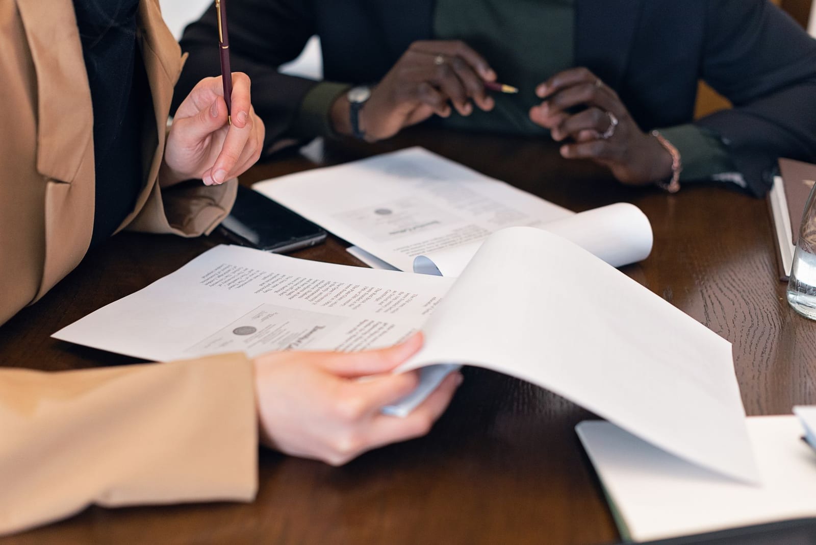 Close-up of professionals reviewing documents during a business meeting in an office setting. health insurance