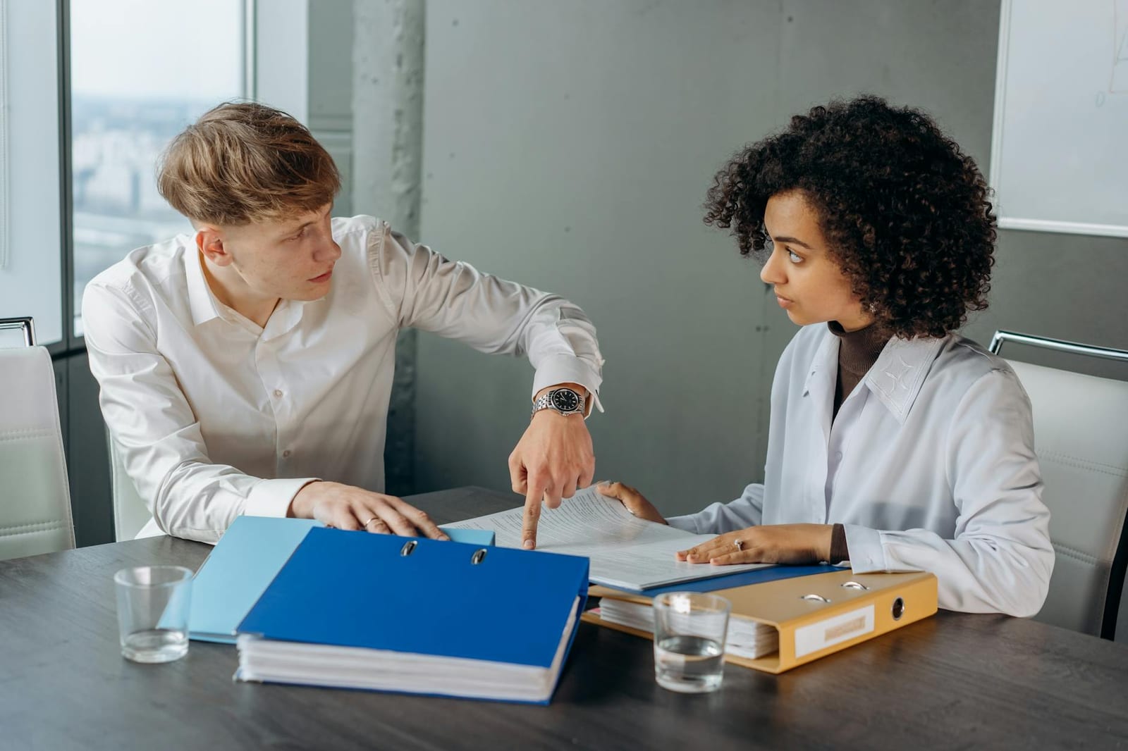 Professional workplace discussion between colleagues reviewing documents at an office table. health insurance