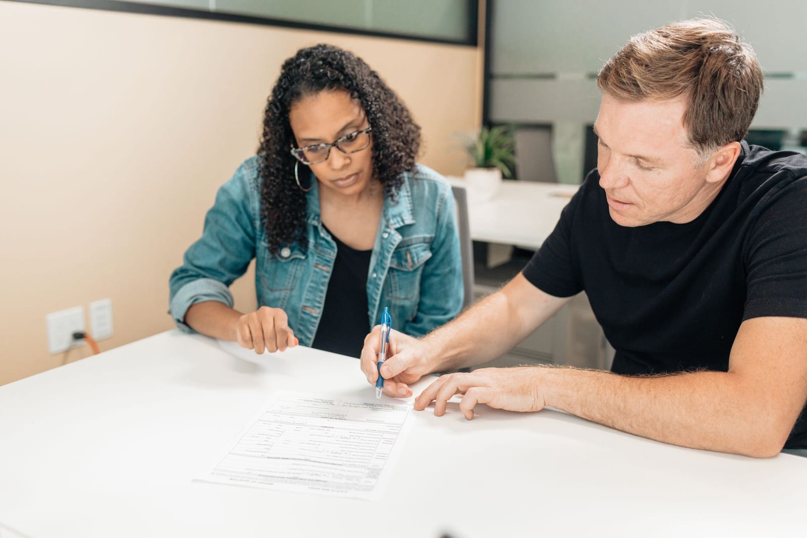 A couple working together to sign important legal documents at a desk in an office setting. health insurance