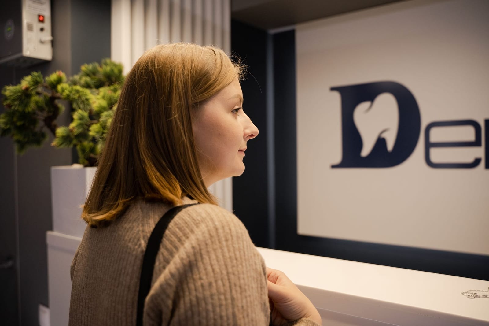 A woman waiting at the dental clinic reception, viewed from the side. Indoor setting. health insurance