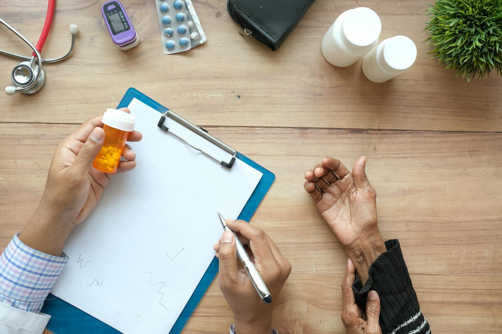 A doctor holds a pill bottle while consulting with an elderly patient. A stethoscope and prescriptions are visible. health insurance