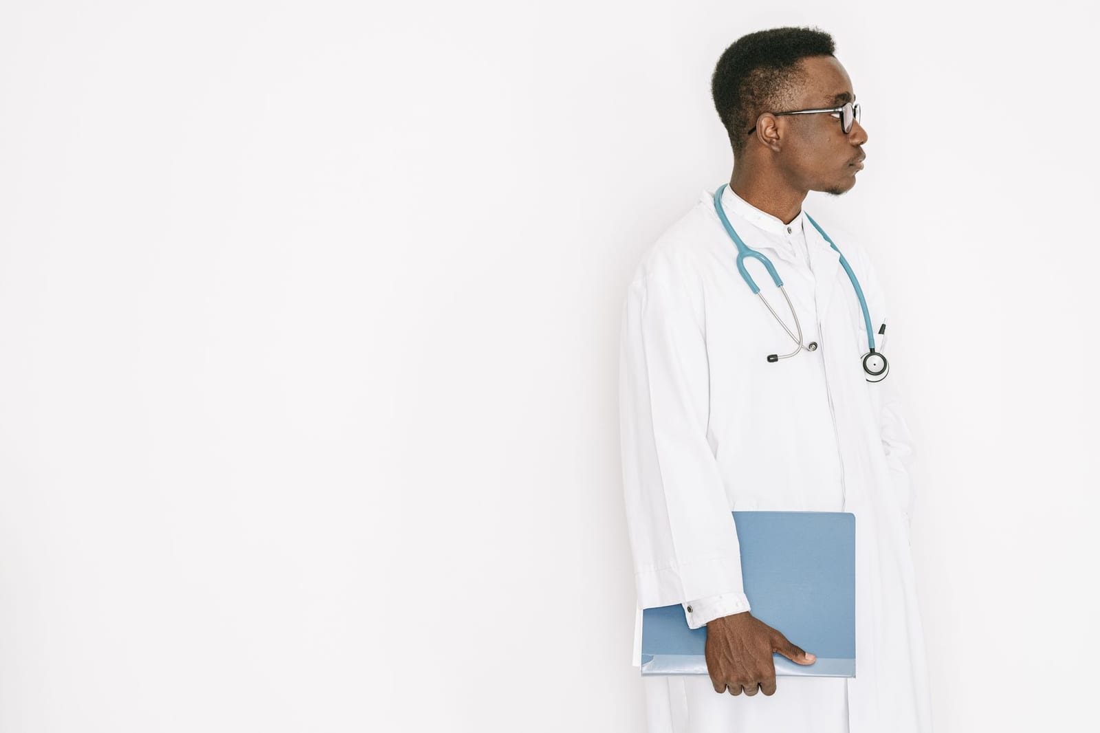 Side profile of a doctor in a medical gown holding a folder with a stethoscope around the neck. health insurance