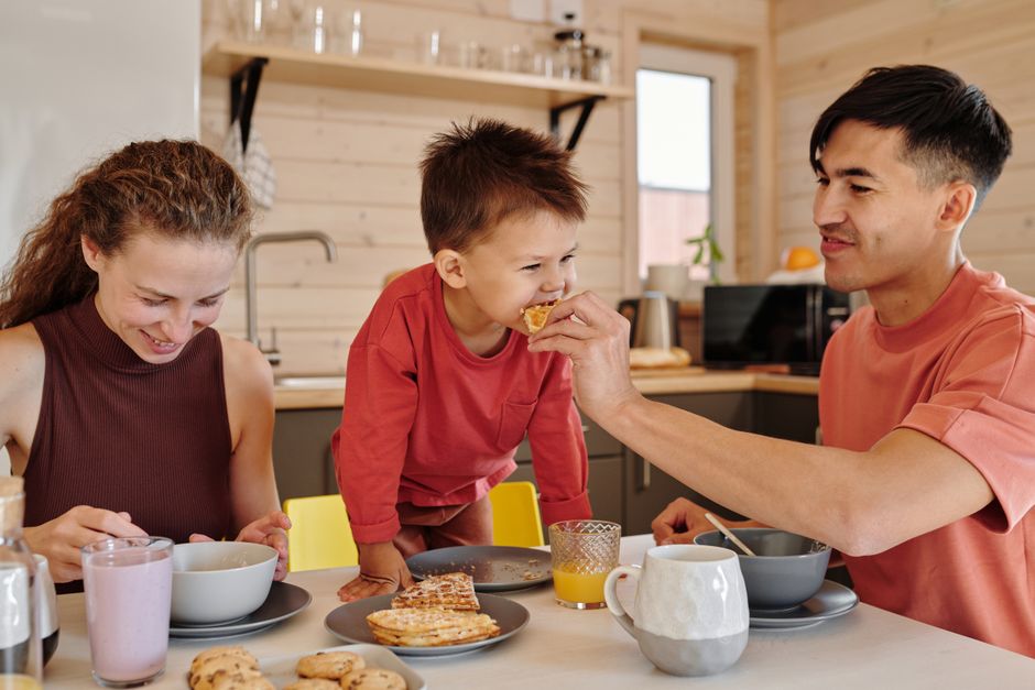 A joyful family of three shares breakfast in a cozy kitchen setting, depicting warmth and togetherness. A joyful family of three shares breakfast in a cozy kitchen setting, depicting warmth and togetherness.