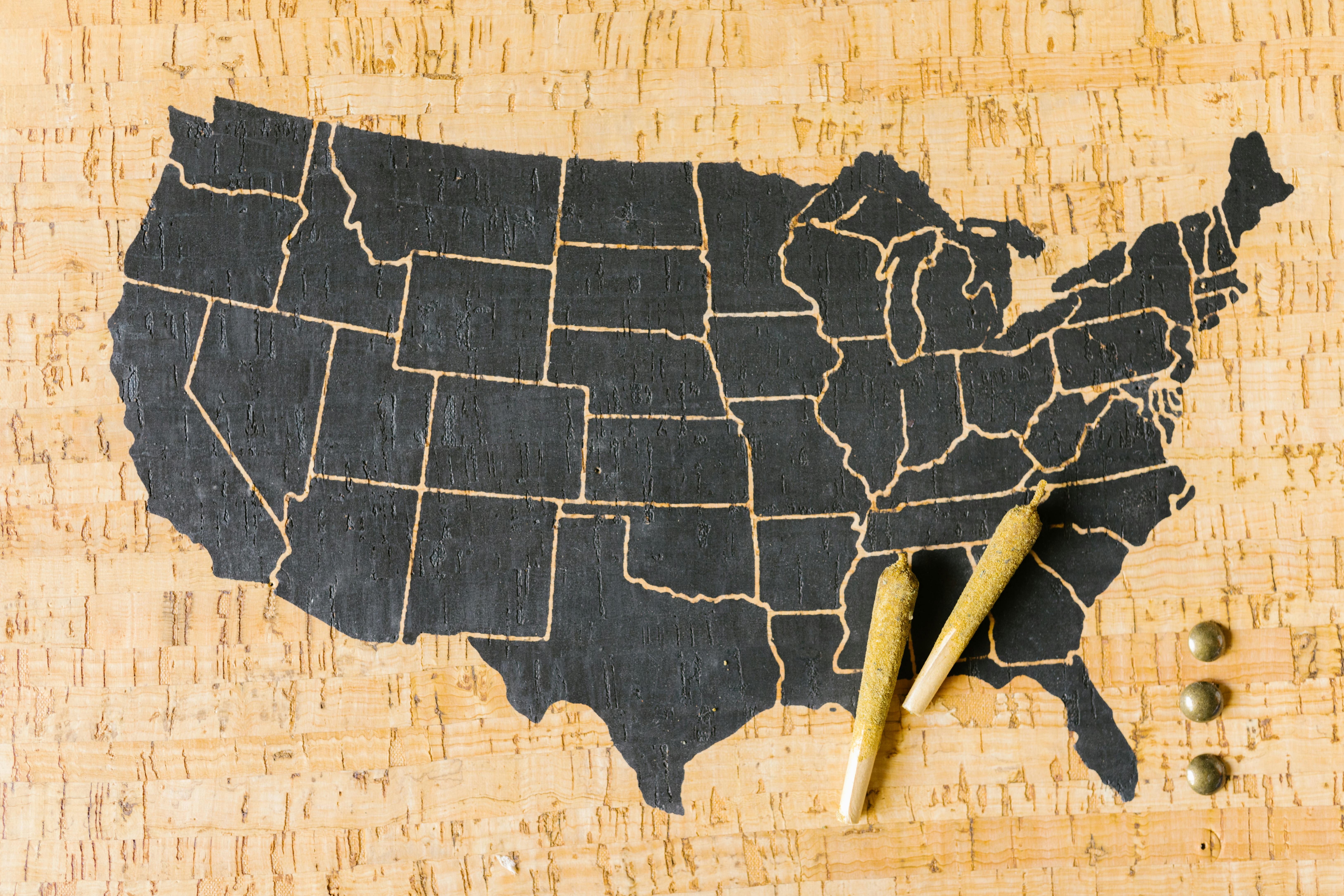 Black silhouette of the United States map carved into a cork surface, representing state-by-state health insurance guides and coverage options.